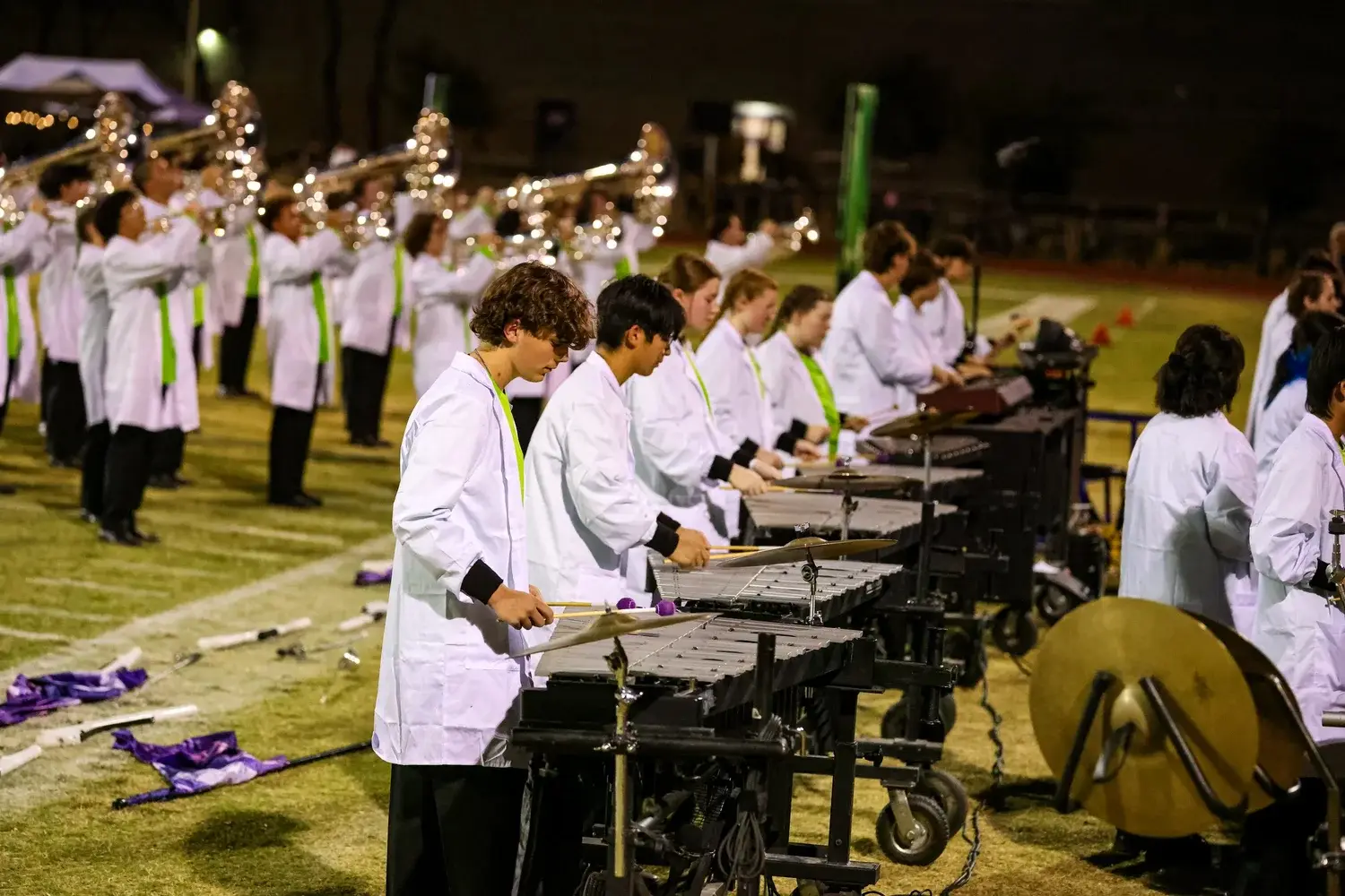 Hamilton Marching Huskies front ensemble and brass performing under the lights