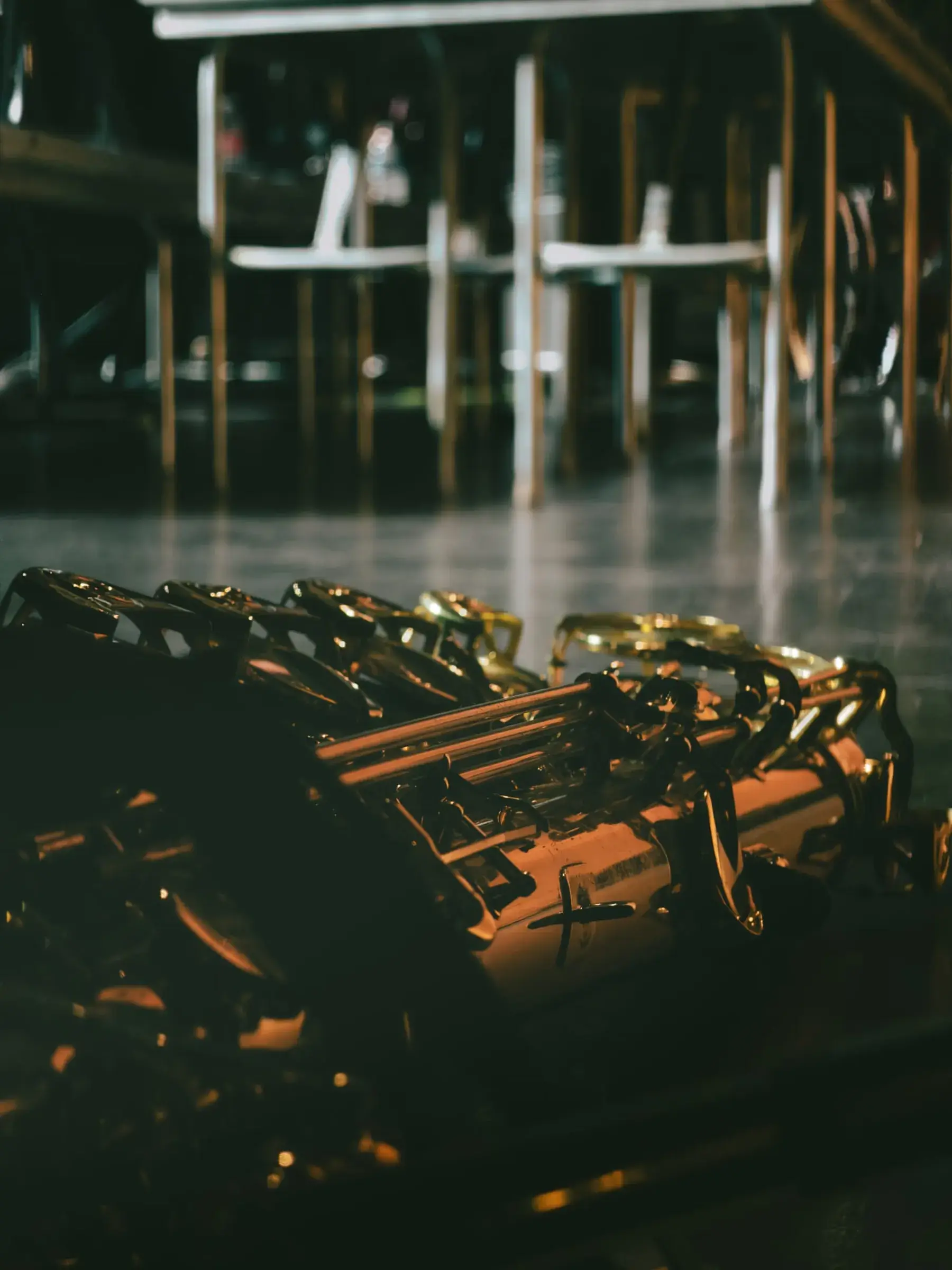 A row of Hamilton saxophones resting on stage under warm light