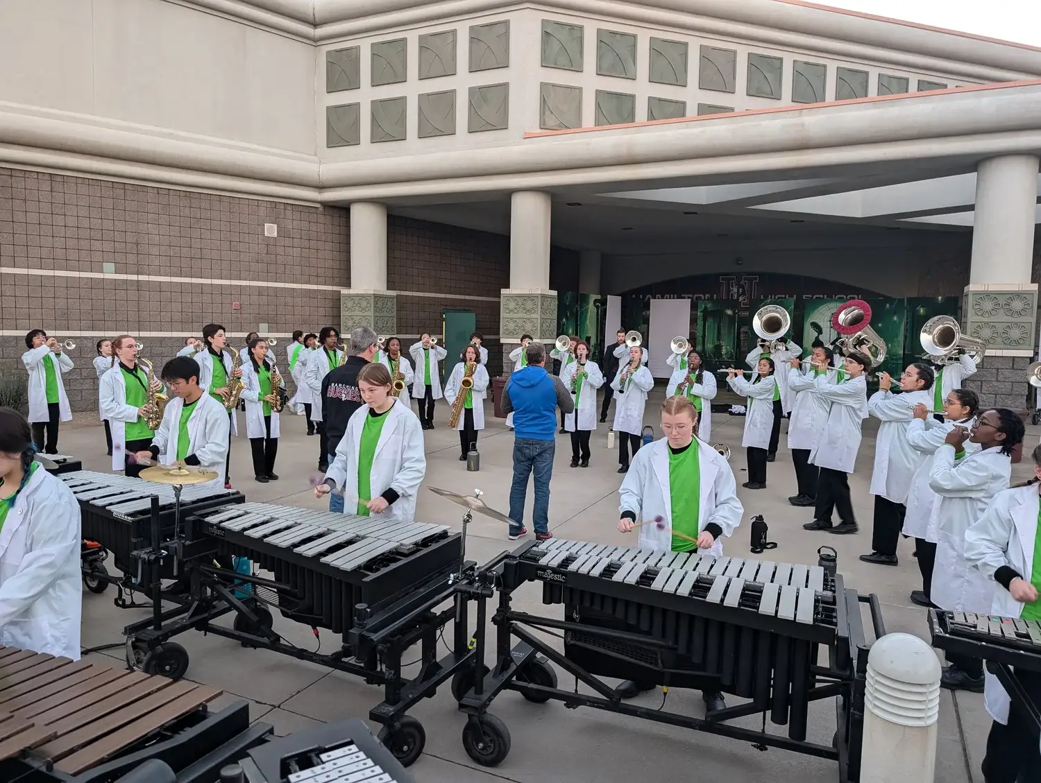 Marching Huskies warming up in lab coats outside Hamilton High School